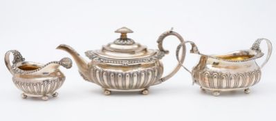 A late Georgian matched silver three piece tea service. of barge shaped outline, with half reeded