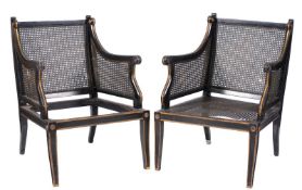 A pair of ebonised and gilt decorated bergere armchairs in the Regency taste, having cane panel