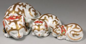 A group of three Japanese Kutani sleeping cats each with gilt markings and wearing iron-red, green