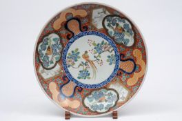 An Arita porcelain charger of circular form the centre enamelled with a an exotic pheasant amongst