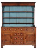 An early 19th Century oak dresser, the shelved superstructure with green painted back, having a