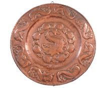 A Newlyn type circular embossed copper charger, mounted as a wall plaque, decorated with dolphins