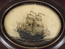 An early 19th Century oval reverse-glass silhouette picture of a frigate, set full sail with figures