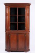An early 19th Century oak corner display cabinet, in two parts, the upper part with a moulded dentil
