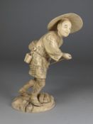 A Japanese carved sectional ivory okimono, of a peasant wearing traditional clothes holding a bamboo