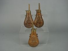 Three Victorian copper powder flasks with repousse hunting dog and wild fowl decoration: (2)