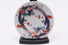 A Japanese Arita dish moulded and painted in ‘Imari’ colours with ribbons, flowers and foliage,