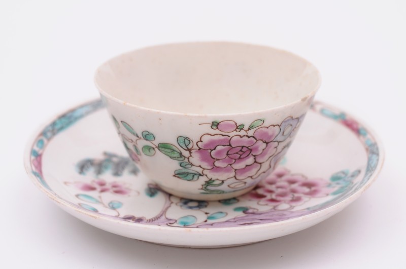 A Bow teabowl and saucer painted in famille rose colours with peony, a willow tree and rockwork, the