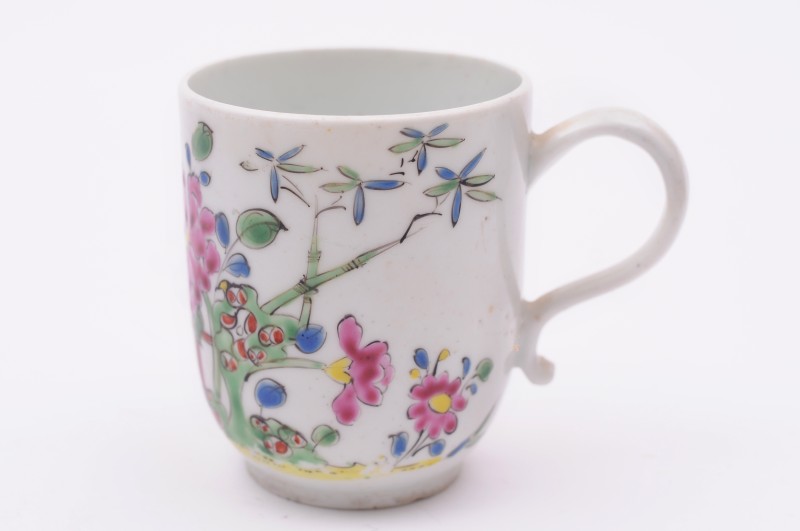 A Longton Hall coffee cup with scroll handle, painted in famille rose enamels with flowers, foliage,