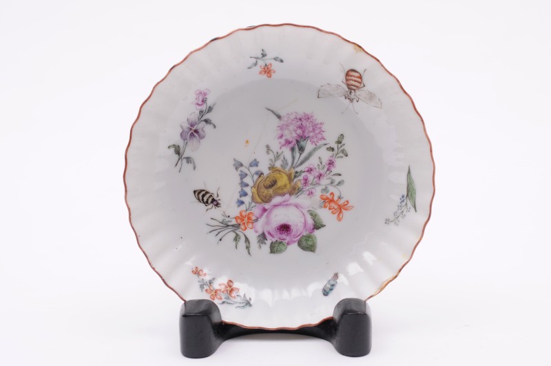 A London-decorated Chinese saucer dish with fluted rim, painted with a large floral bouquet,