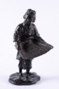 A Japanese bronze figure of a peasant woman dressed in traditional costume and holding a grain
