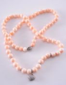 A pink coral and diamond necklace composed of pink coral beads, graduated from 9.2mm to 11.5mm