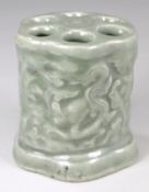 A Chinese celadon glazed brush holder of pierced hexagonal profile embossed and carved with