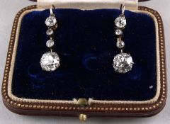 A pair of diamond four stone drop earrings: each with a round old brilliant cut diamond