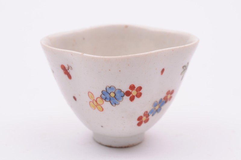 A Bow teabowl of quadrilobed form , painted with scattered flowers outlined in black in the Kakiemon