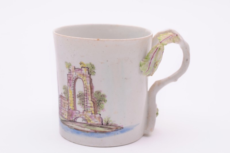 A Longton Hall coffee can of cylindrical form with rustic branch handle, painted in ‘Castle Painter’
