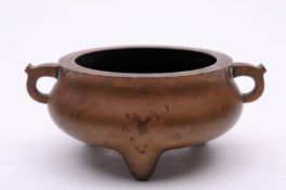 A Chinese bronze tripod censer of compressed baluster form with flattened rim and ‘eared’ loop