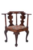 An 18th Century carved walnut corner elbow chair, decorated with acanthus leaves and flowerheads,