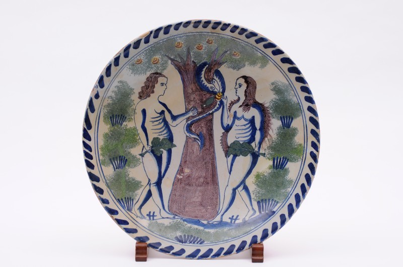 A Bristol delft Adam and Eve blue dash charger painted in blue, green, manganese, yellow and iron-