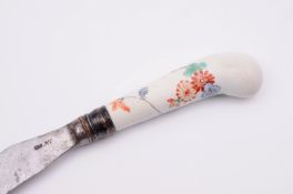 A Chantilly pistol grip knife handle painted in the Kakiemon style with a flowering branch and an