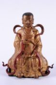 An 18th century Chinese gilded metal seated deity wearing traditional costume, mounted on a wood