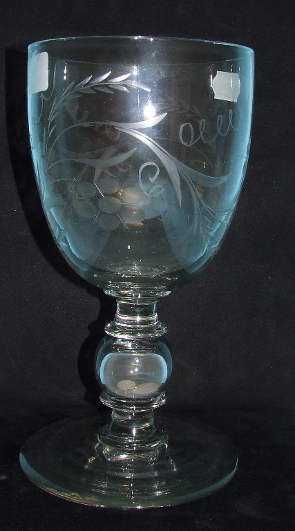 A large glass goblet, with etched decoration and coins in the stem, 25.5 cm high