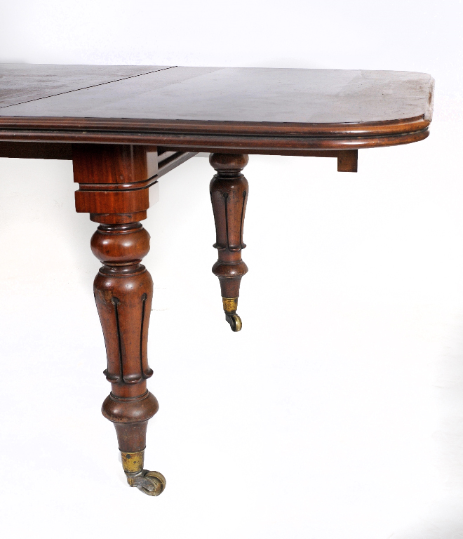 A Victorian mahogany pull out extending dining table, the rounded rectangular top inset four extra