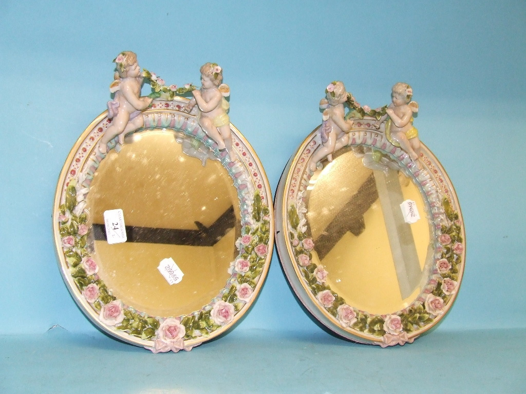 A pair of wall mirrors, decorated cherubs (2)