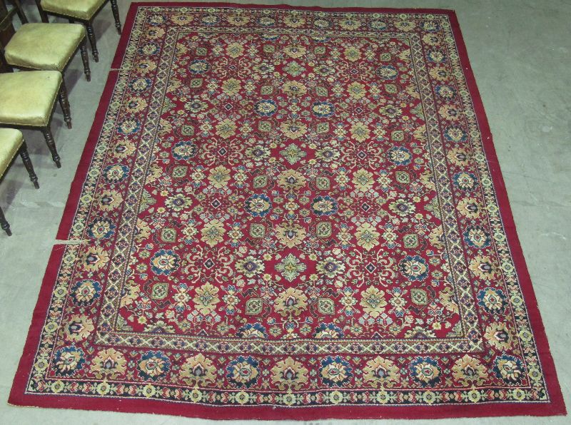 A LARGE RUG WITH ALL OVER FLORAL AND COLOURED MOTIFS ON A RED GROUND 355 X 272CM (CUT) TOGETHER WITH