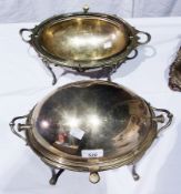 Two silver-plated breakfast dishes of oval and bulbous form with revolving lids, one on scroll