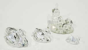 Three cut glass Swarovski swans and a Swarovski glass miniature village on stand (4)