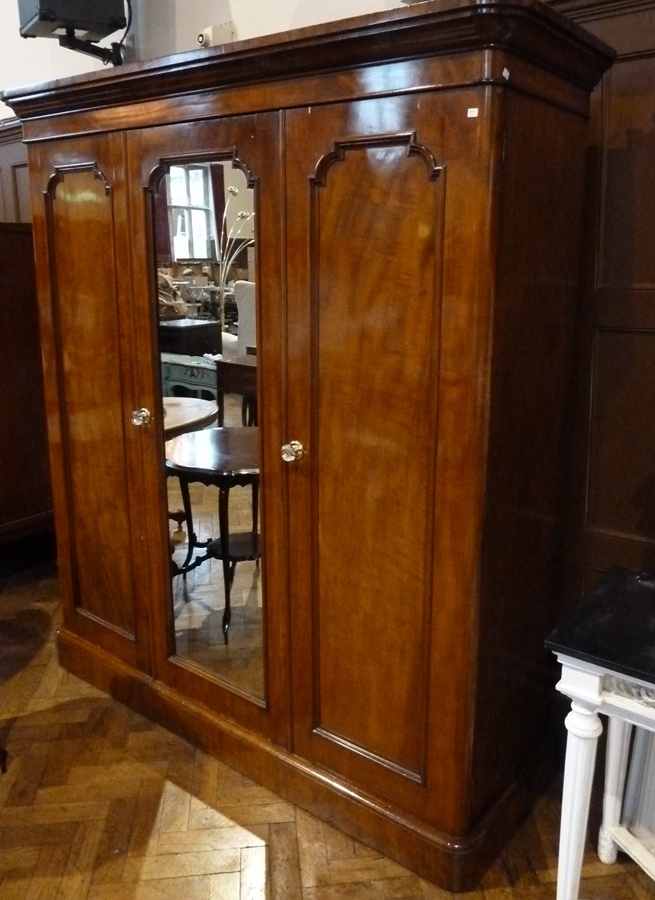 A Victorian mahogany compactum with ogee cornice, one mirrored panel, and two framed panel doors,