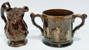 A 19th century treacle glazed loving mug,  decorated with moulded low relief figures, 17cm high,