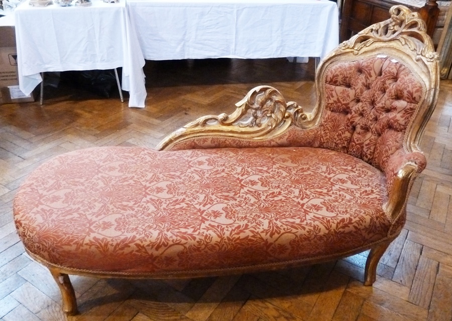 A modern gilt painted wood and upholstered chaise longue, foliate and gilt carved surround, red