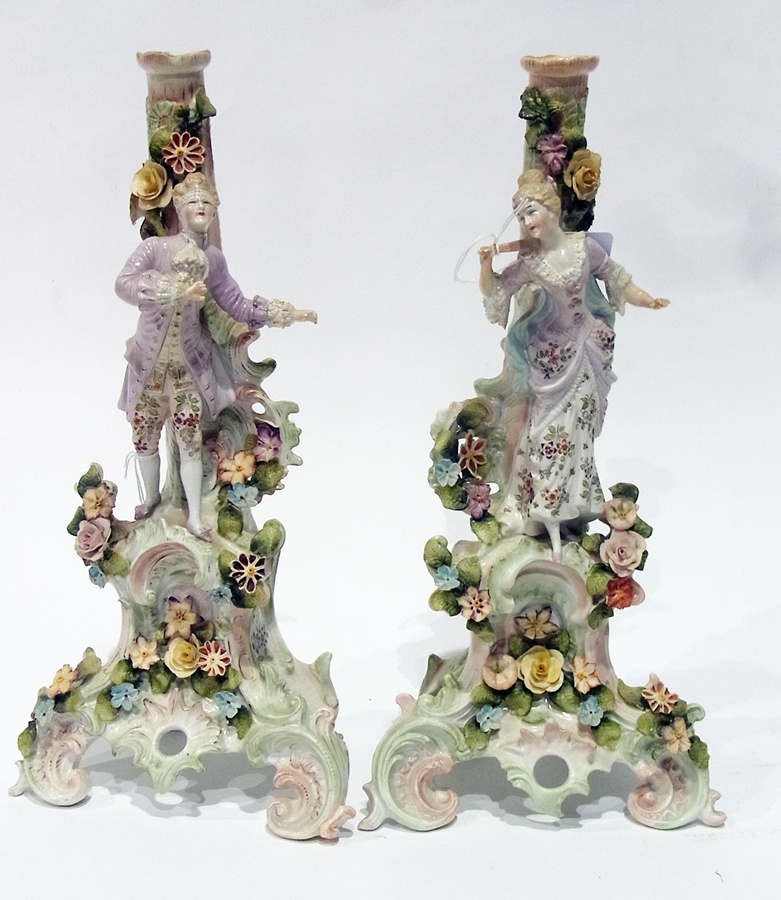 Pair Dresden style candlesticks, each floral encrusted column, one with male figure, the other