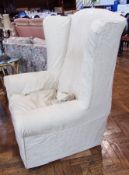 A pair of high backed wing arm chairs with beige upholstery on bun feet