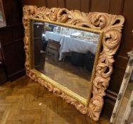 Large modern gilt framed wall mirror, heavy foliate decoration, highlighted with pink around a large