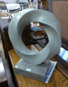 Contemporary grey composite circular twisted sculpture, on a grey plinth, 61cm high approximately