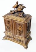 Black Forest carved walnut table cabinet, with partridge surmount, pair foliate carved panel doors