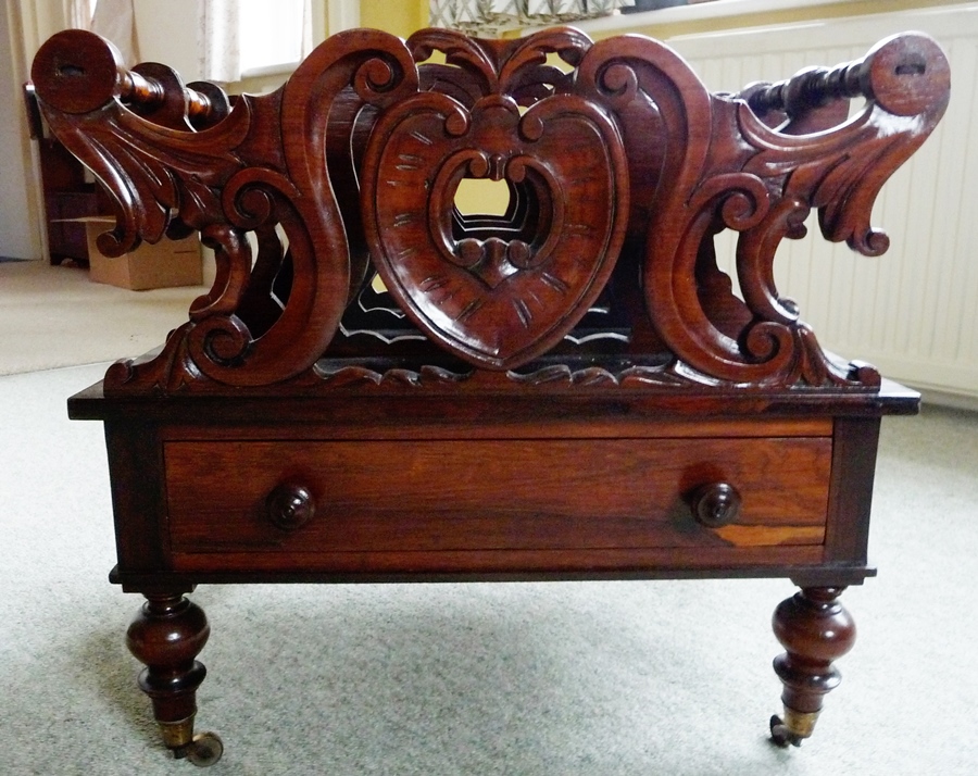 Victorian rosewood Canterbury, scroll carved with drawer below on turned supports and casters,