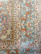 A large Persian silk carpet, central cartouche of red and green, floral decorated with running