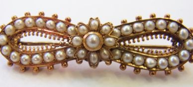 Victorian gold-coloured metal and seedpearl bar brooch in the form of a bow centred by a flowerhead