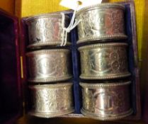 Cased set of silver plate napkin rings, embossed with flower decoration and numbered 1-6