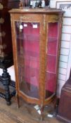 Early 20th century mahogany serpentine vitrine, with gilt coloured metal relief decoration, with