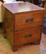 A pair of teak bedside campaign chests of two drawers with brass mounts to corners and brass