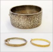 Silver bangle, foliate scroll engraved, another narrower bangle and a gold-coloured metal bangle