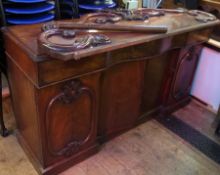 Victorian mahogany pedestal sideboard with raised scroll carved back, serpentine front fitted