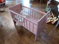 A painted wooden dolls crib with Dutch nursery rhyme characters painted on ends and a little quilt
