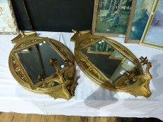 A pair of late nineteenth century gilded oval girandoles with broken arch pediments, rectangular
