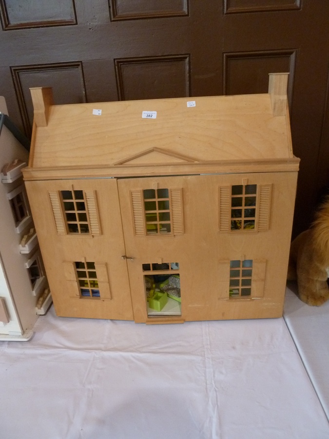 A large wooden dolls house, unpainted, with various painted wooden dolls house furniture